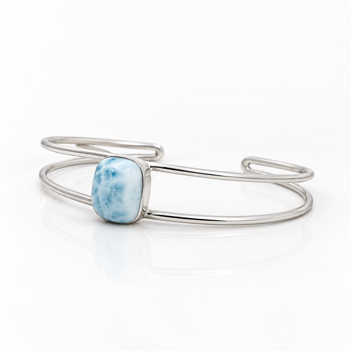 Cushion-shaped Larimar sterling silver double-wire cuff bracelet, left angled view on glossy white