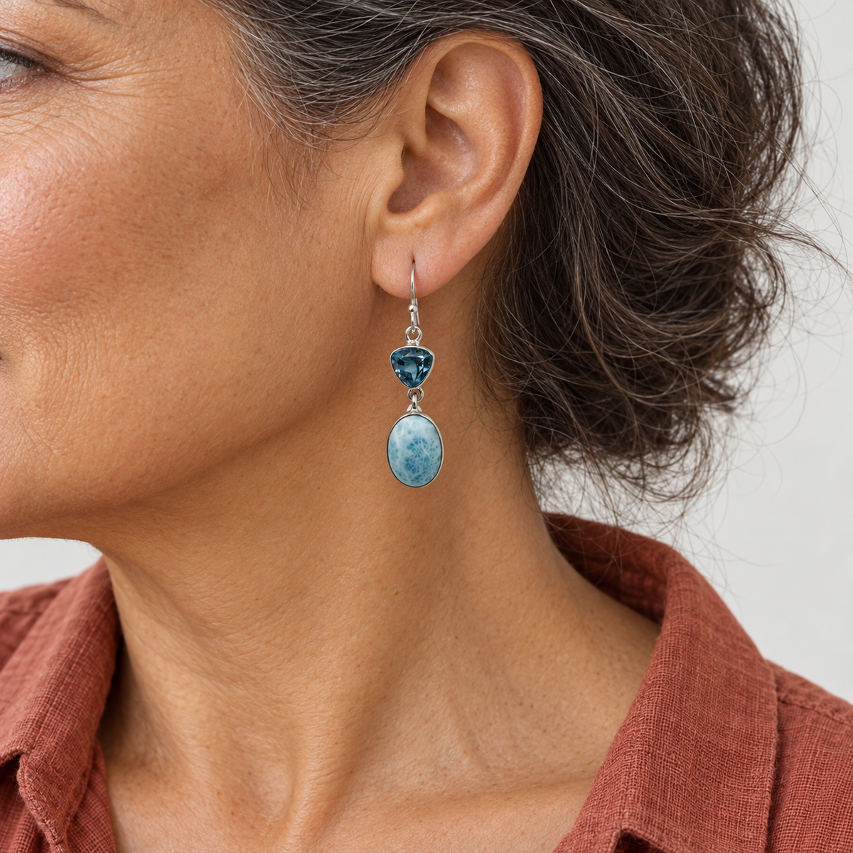 Larimar and triangular blue gemstone drop earring on a model in terracotta linen, approximately scaled to 0.4 inch width and 1.6 inch total length.