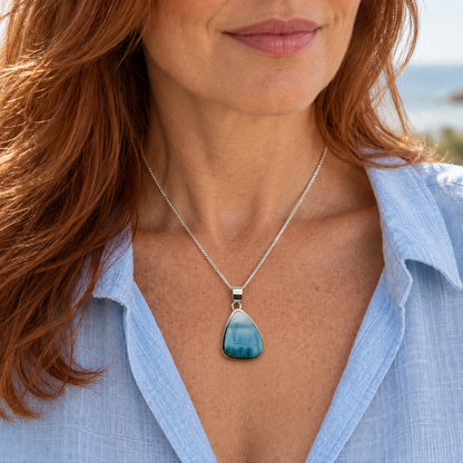 Auburn-haired woman wearing a teardrop Larimar necklace at 1 inch wide by 1.6 inches high