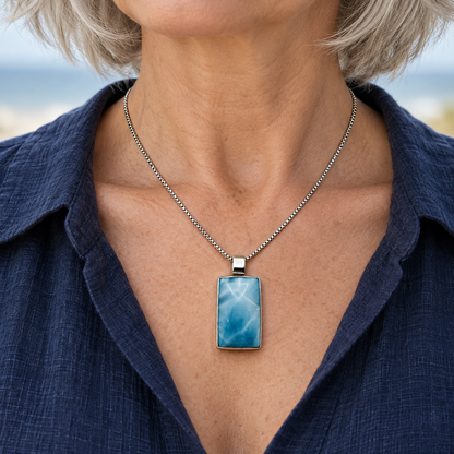 Silver-haired woman wearing a 0.7 by 1.4 inch Larimar Blue Passage necklace on an 18 inch sterling silver chain