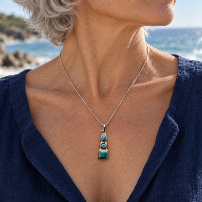 Silver-haired woman in navy linen wearing a 0.4 by 1.6 inch three-stone Larimar necklace
