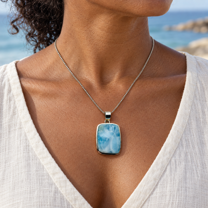 Woman wearing a 1 by 1.7 inch rectangular Larimar necklace with a cream linen top