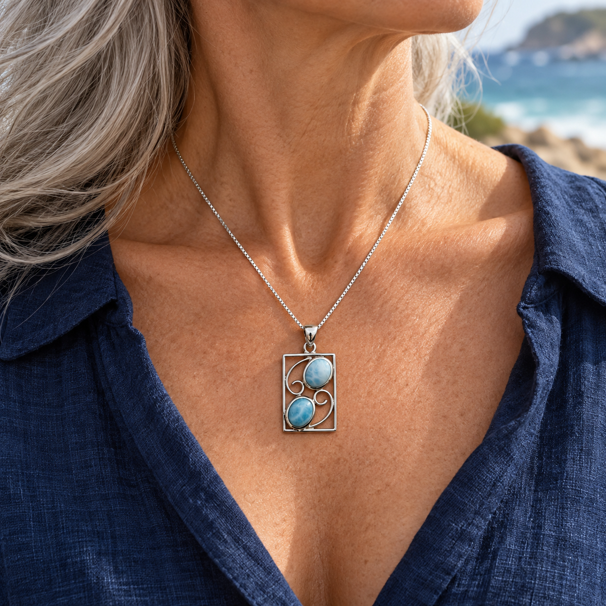 Two-stone rectangular Larimar necklace worn by a silver-haired woman in navy