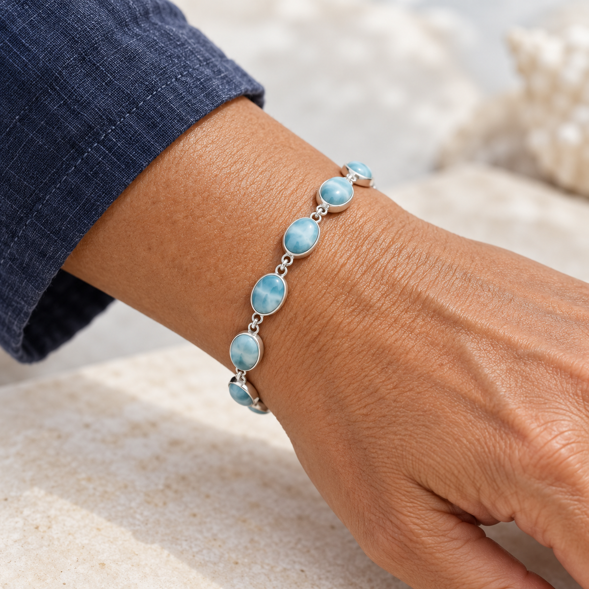 Larimar oval-stone sterling silver link bracelet worn on a model's wrist with a navy sleeve.