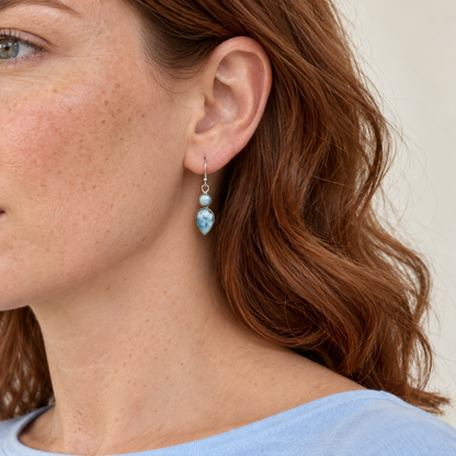 Auburn-haired model in a pale blue shirt wearing two-stone Larimar drop earrings; approximate scale mockup.