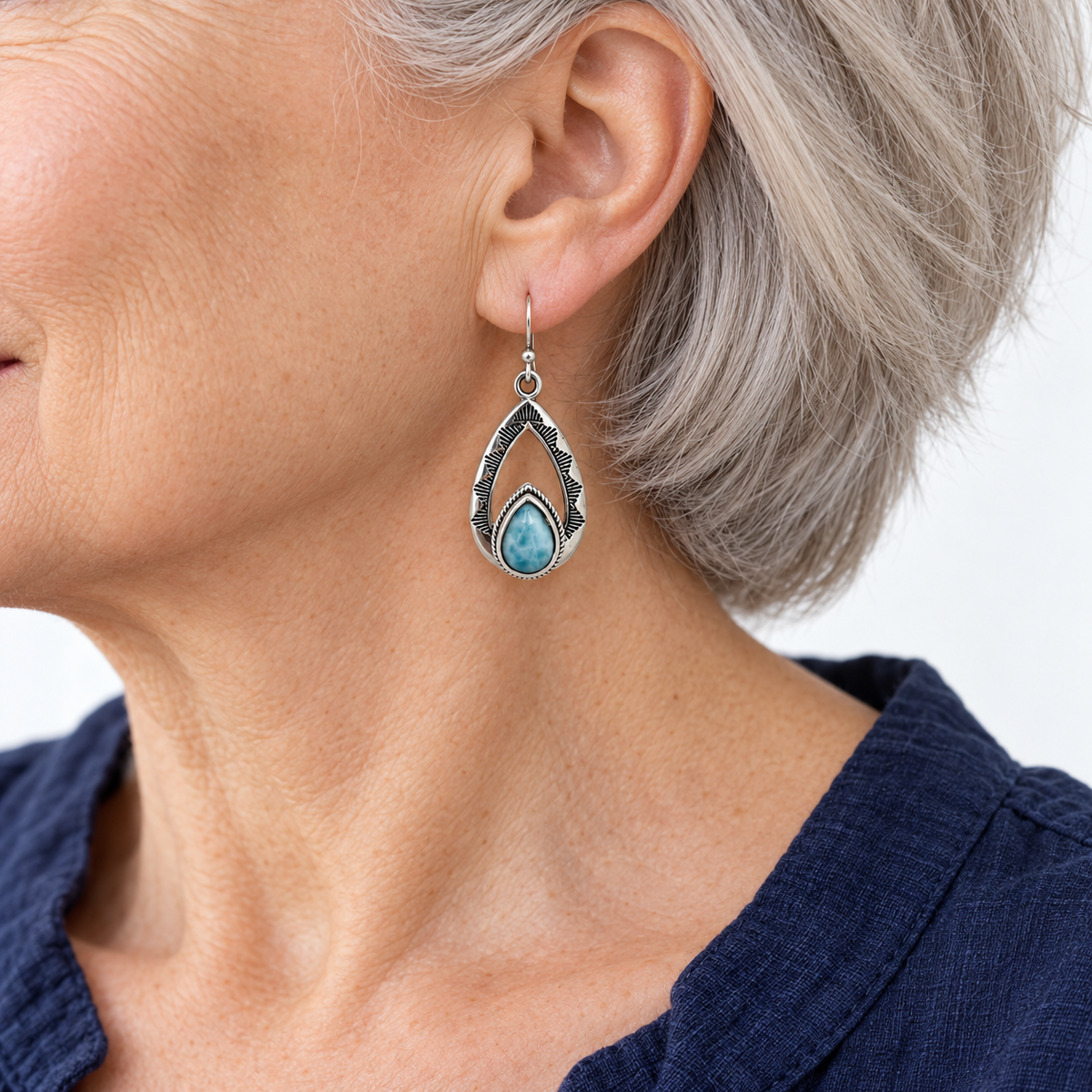 Open teardrop Larimar sterling silver earring worn by a silver-haired model in navy, approximate scale for 0.6 inch width and 1.5 inch total length.