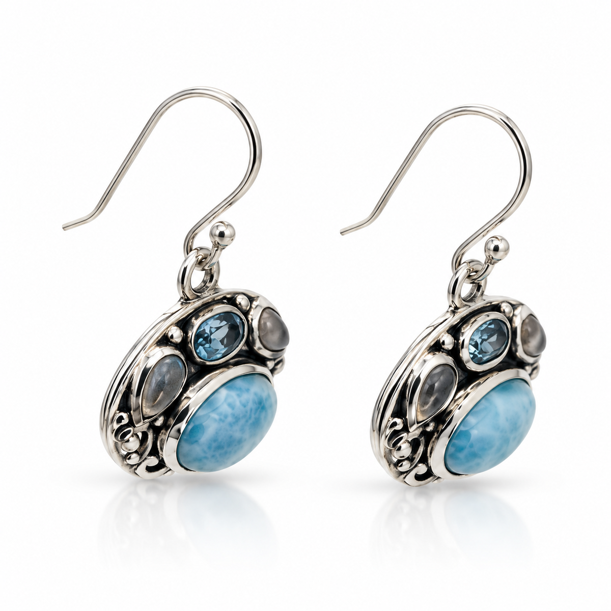 Angled view of ornate oval Larimar earrings with polished sterling silver scrollwork and dark recessed finish.