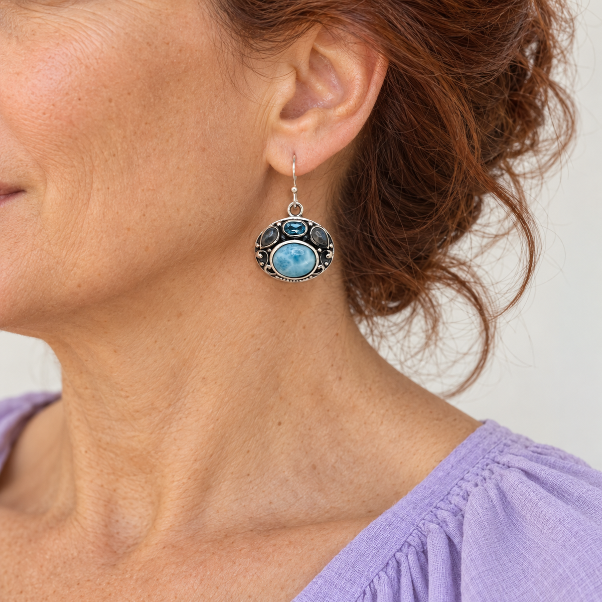 Ornate oval Larimar sterling silver earring on an auburn-haired model in lavender, approximate scale for 0.8 inch width and 1.2 inch total height.