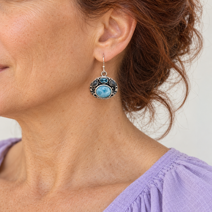 Ornate oval Larimar sterling silver earring on an auburn-haired model in lavender, approximate scale for 0.8 inch width and 1.2 inch total height.