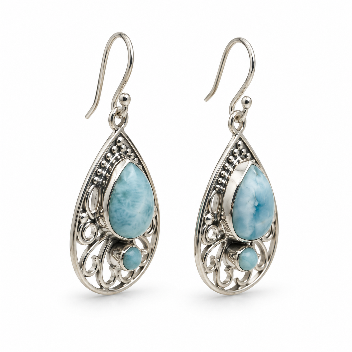 Angled view of teardrop Larimar earrings showing silver bezel depth and open scrollwork on white.