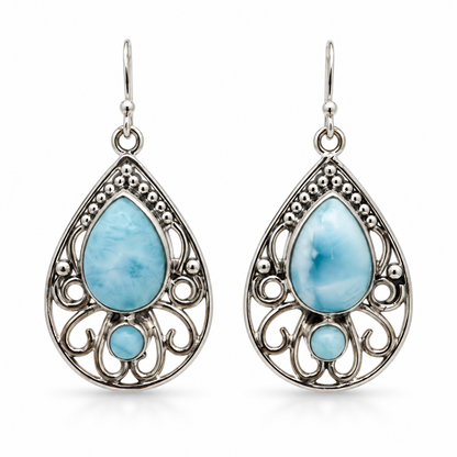 Front view of teardrop Larimar earrings with round Larimar accents and open silver scrollwork on white.