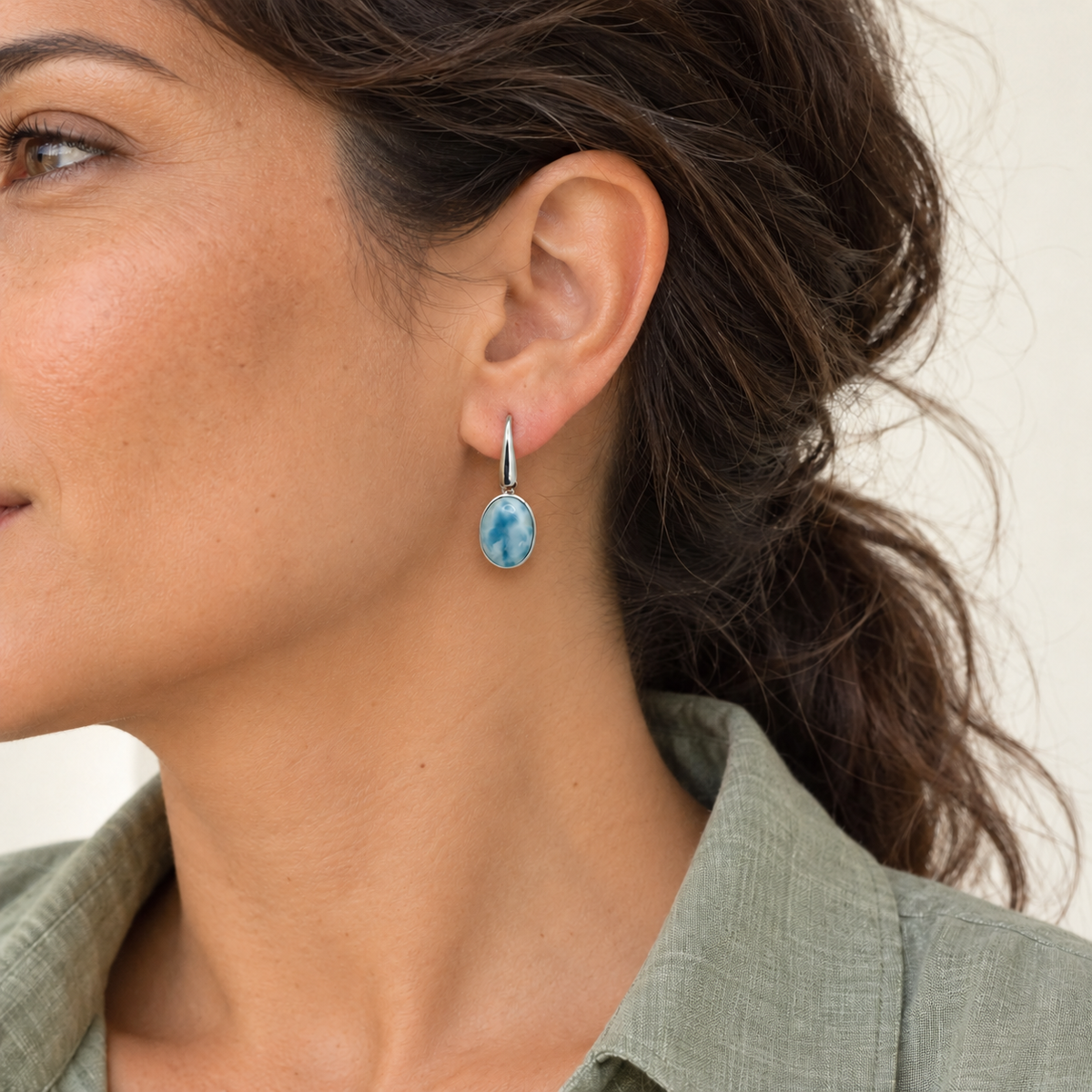 Oval Larimar sterling silver earring on a brunette model in a sage linen shirt, approximately 0.4 inches wide by 1.2 inches total length.