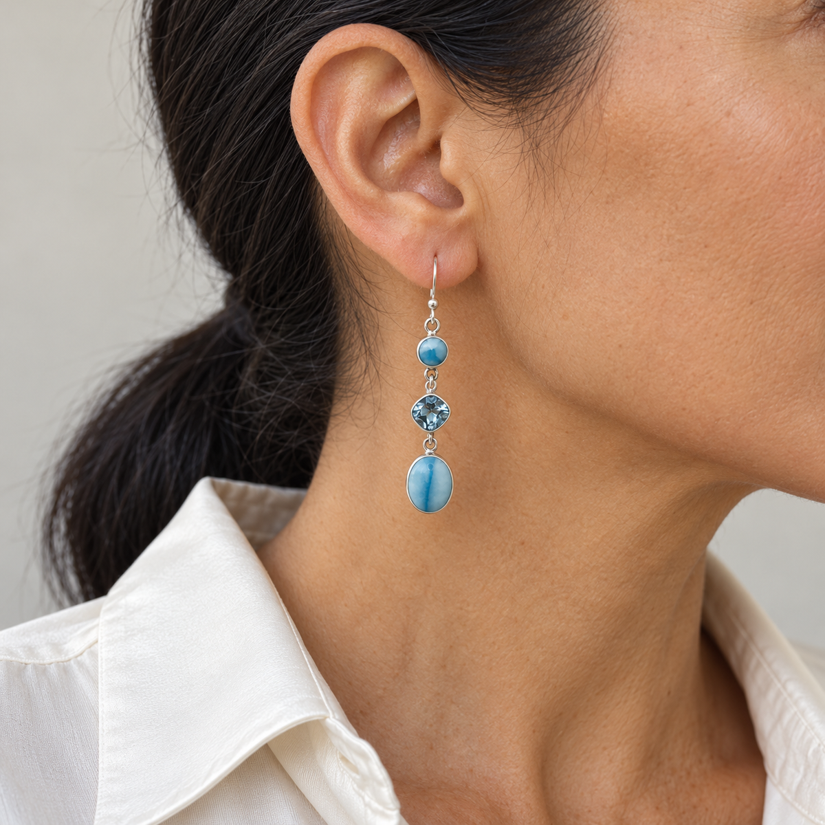 Three-stone Larimar sterling silver drop earring on a dark-haired model in a cream collared shirt, approximate scale for 0.3 inch width and 1.9 inch total length.