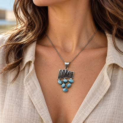 Woman wearing 1 inch by 1.2 inch Larimar Tidal Cascade necklace on an 18 inch sterling silver box chain
