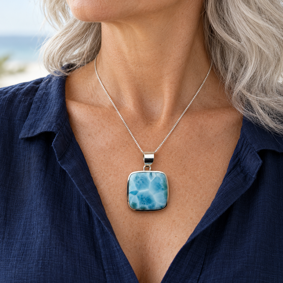 Silver-haired woman wearing a rounded-square Larimar necklace at 1.3 inches wide by 1.8 inches high