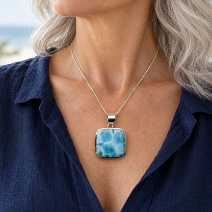 Silver-haired woman wearing a rounded-square Larimar necklace at 1.3 inches wide by 1.8 inches high