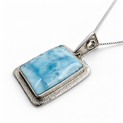 Rectangular Larimar necklace with textured sterling silver frame, side-profile view on glossy white
